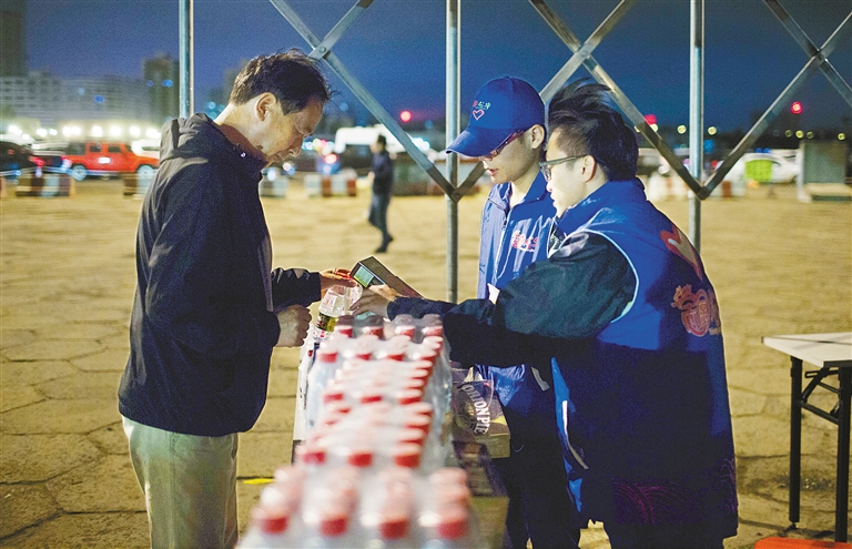 海口港区内，海口市龙华区志愿者为滞留旅客提供面包和瓶装水