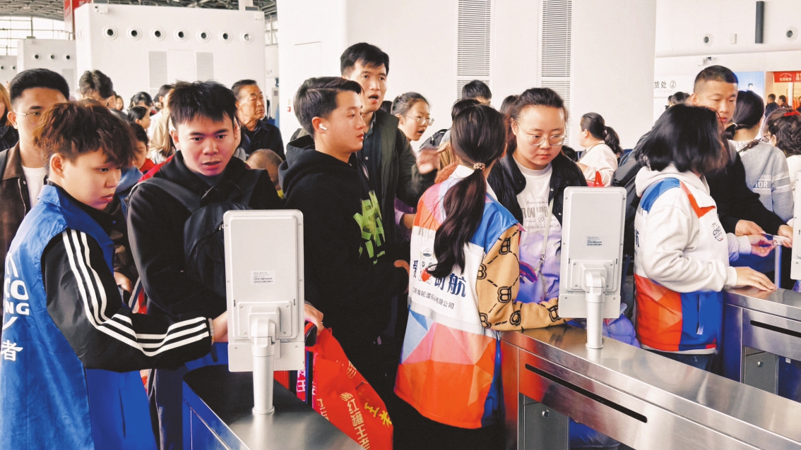在海口新海港，志愿者协助过海旅客通过安检口