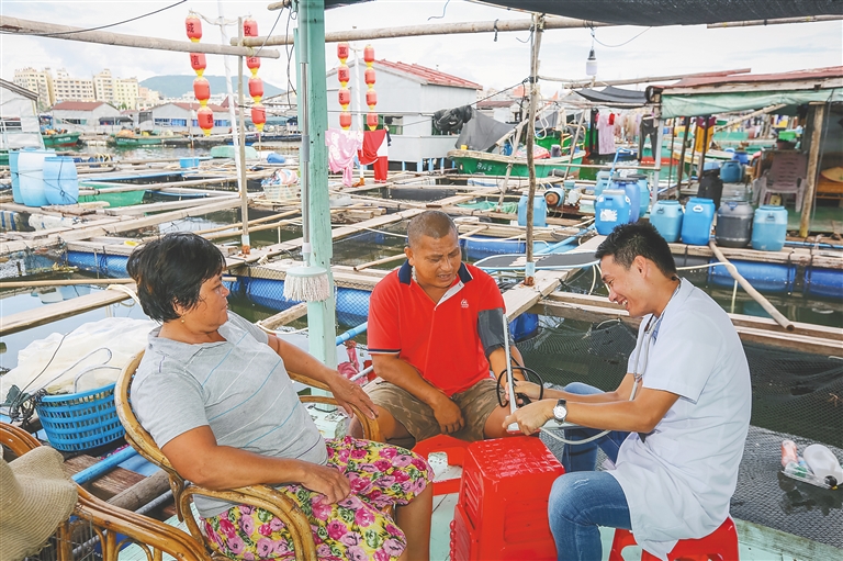 在陵水新村镇，家庭医生曾祥鹏坐船入户，为村民检查身体。